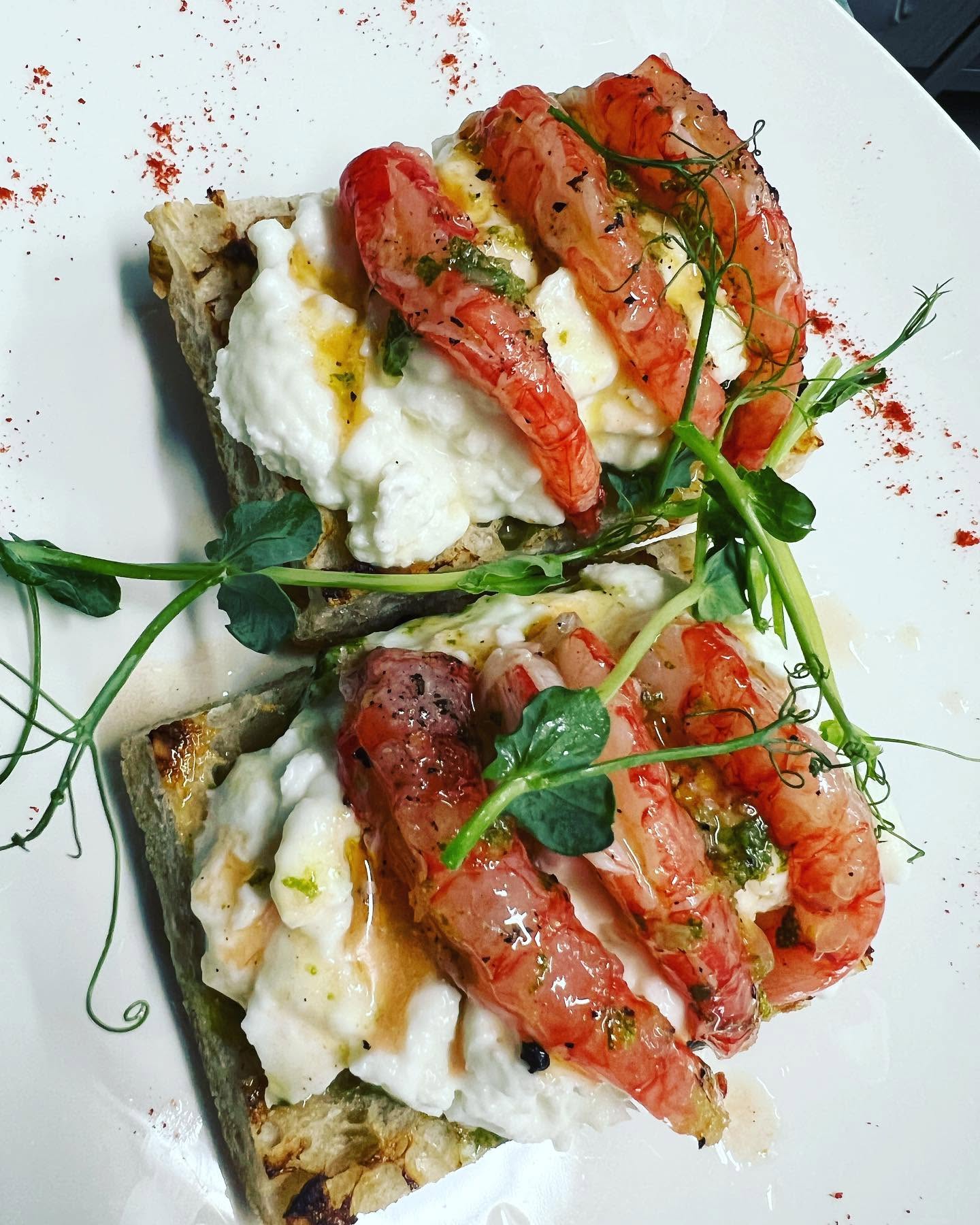 Prawns served on toast with soft cheese and greens